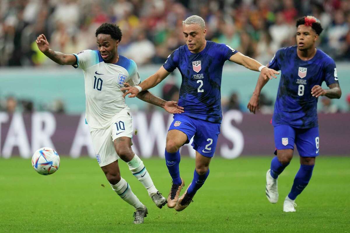 Sergino Dest of the United States, centre, challenges for the ball with England's Raheem Sterling during the World Cup group B soccer match between England and The United States, at the Al Bayt Stadium in Al Khor, Qatar, Friday, Nov. 25, 2022.