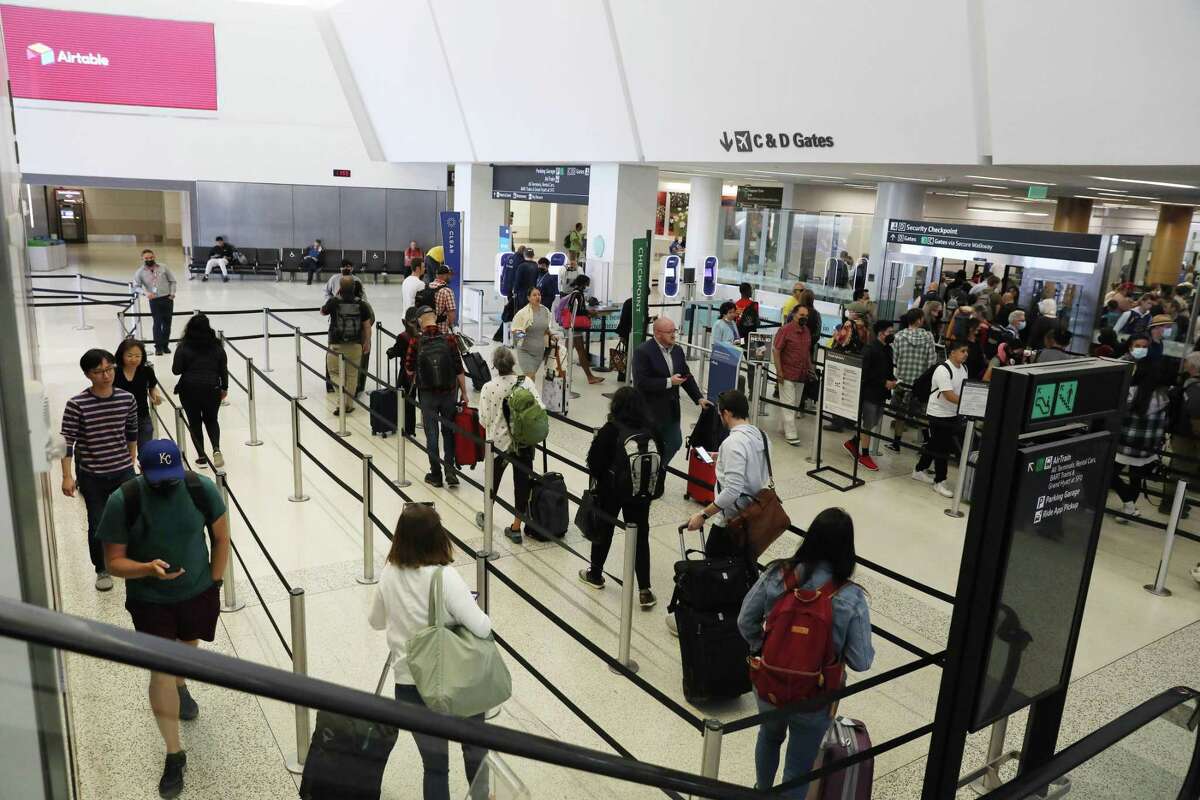 Passengers line up for a security check at San Francisco International Airport. The World Health Organization now recommends international airline travelers wear masks to slow the spread of the highly contagious XBB.1.5 omicron subvariant.