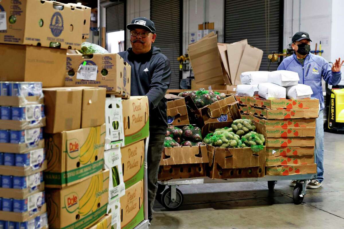 Miguel Sanchez (left) helps haul pallets at Alameda County Food Bank in Oakland. The organization estimates that 1 in 4 Alameda County residents is experiencing food insecurity, up from 1 in 5 before the pandemic