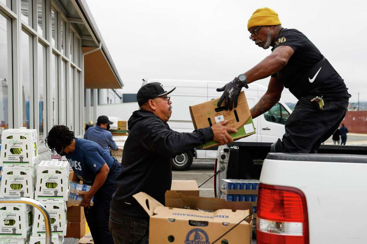 Harold Brooks (left) of the Alameda County Food Bank helps Miguel Sanchez of Primera Iglesia Presbiteriana Hispana loading his truck with goods to take back to the church.