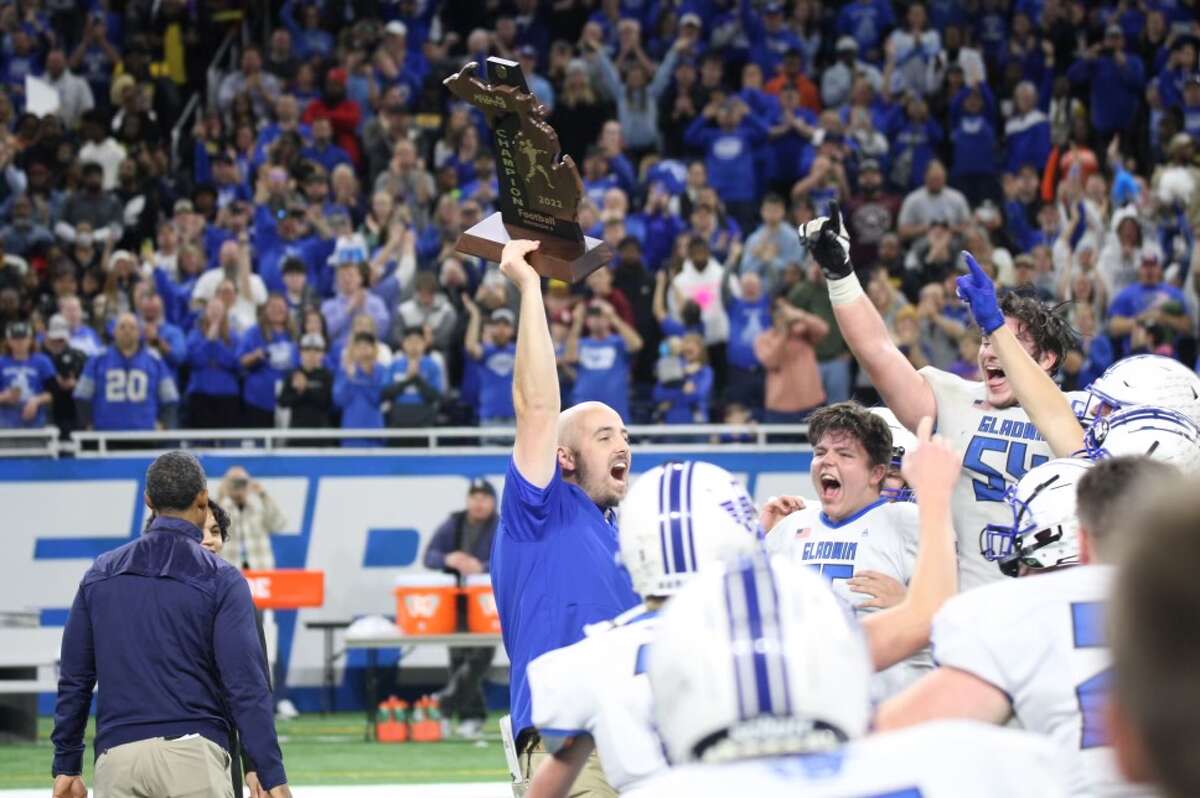 Gladwin coach Marc Jarstfer raises the trophy after Saturday's Division 5 state championship game against Frankenmuth at Ford Field in Detroit, Nov. 26, 2022.