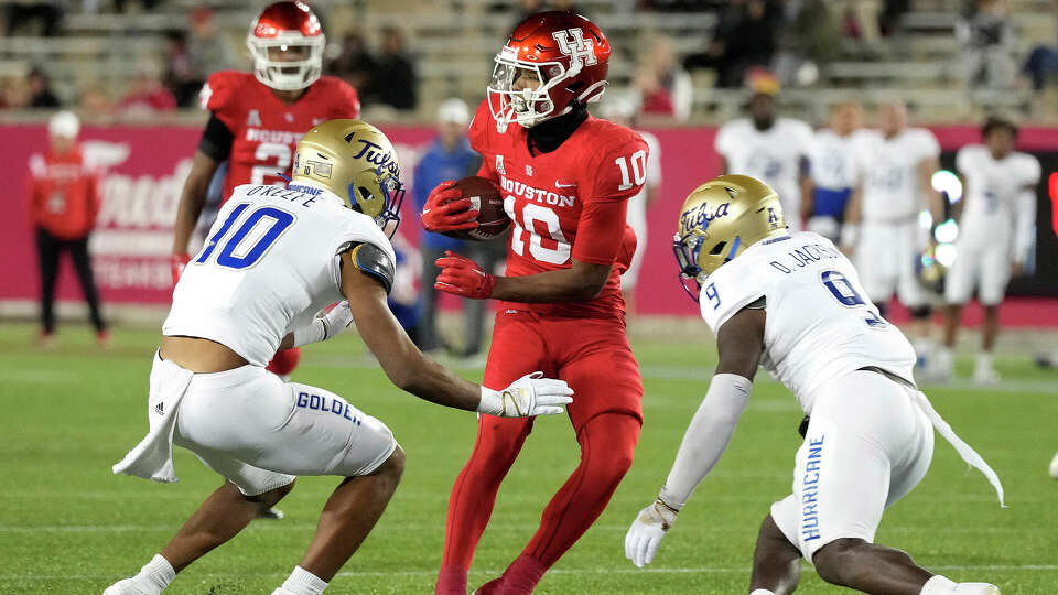 Houston Cougars wide receiver Matthew Golden (10) tries to avoid being tackled by Tulsa Golden Hurricane safety Sean O'Keefe (10) and safety Daiquain Jackson (9) during the first half of an NCAA football game at TDECU Stadium on Saturday, Nov. 26, 2022 in Houston .