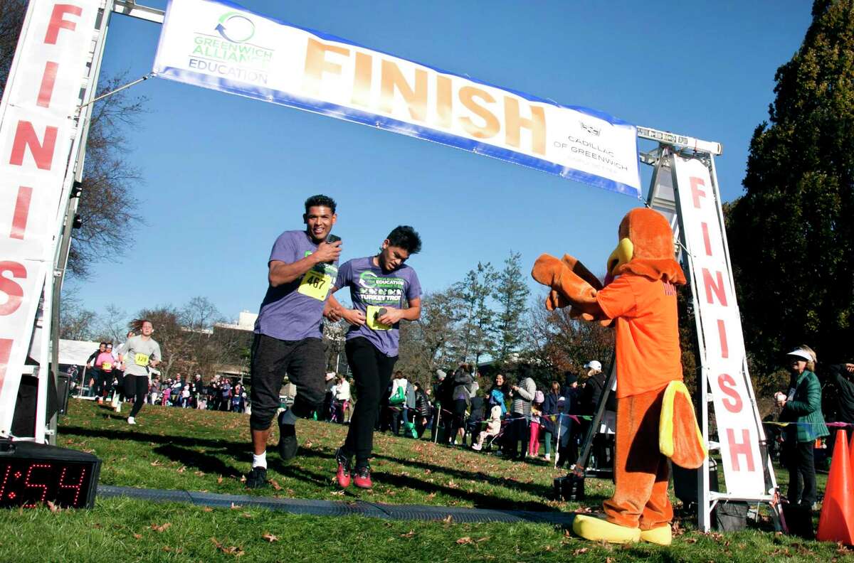 Raymundo Zahuantitla, left, and his son Ignacio finish the race together and are cheered on by a turkey mascot.