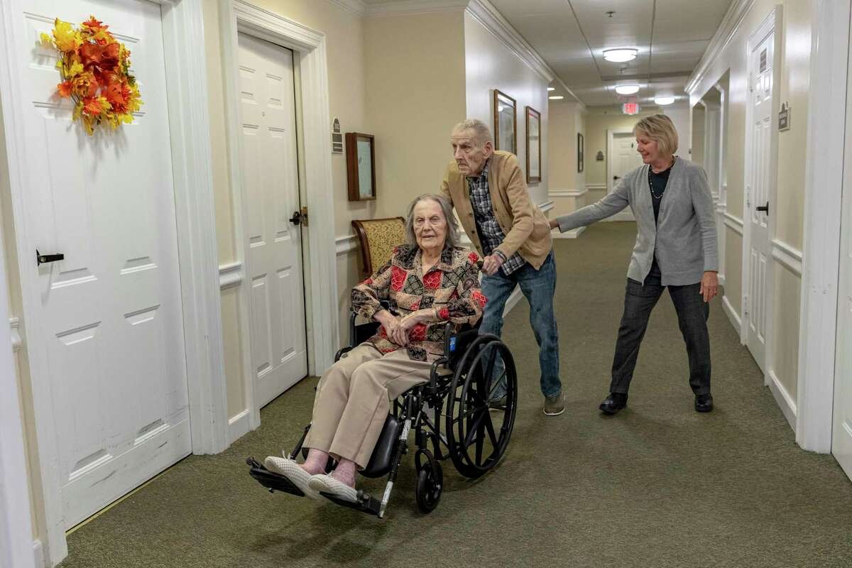 David Grossett, 93, pushes his wife Edna Mae, 90, as their daughter Mary Wise steadies him in the hallway of The Gardens of Castle Hills on Nov. 17, 2022. The couple met at a dance in 1956, when he was a young soldier, and the spark was immediate. Recently, the Grossetts celebrated their 66th wedding anniversary.