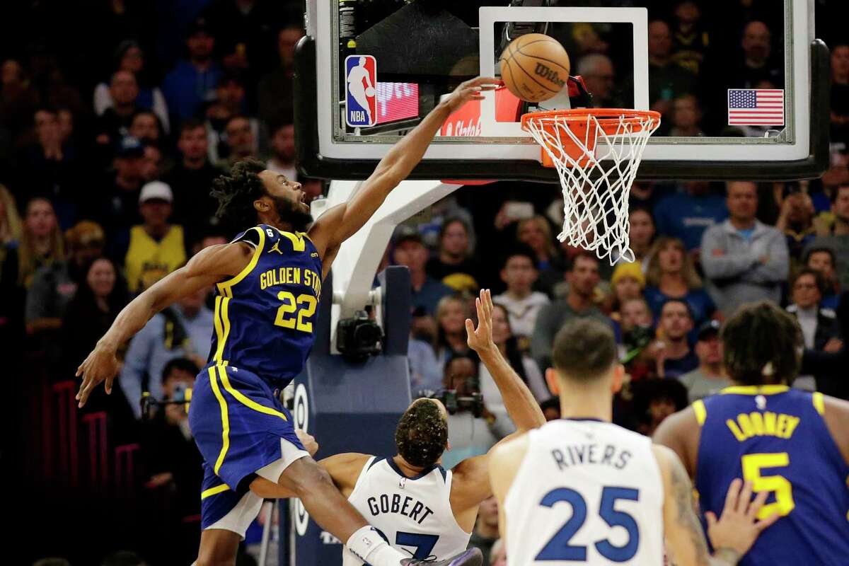 Golden State Warriors forward Andrew Wiggins (22) dunks over Minnesota Timberwolves center Rudy Gobert (27) during the first quarter of an NBA basketball game Sunday, Nov. 27, 2022, in Minneapolis. (AP Photo/Andy Clayton-King)