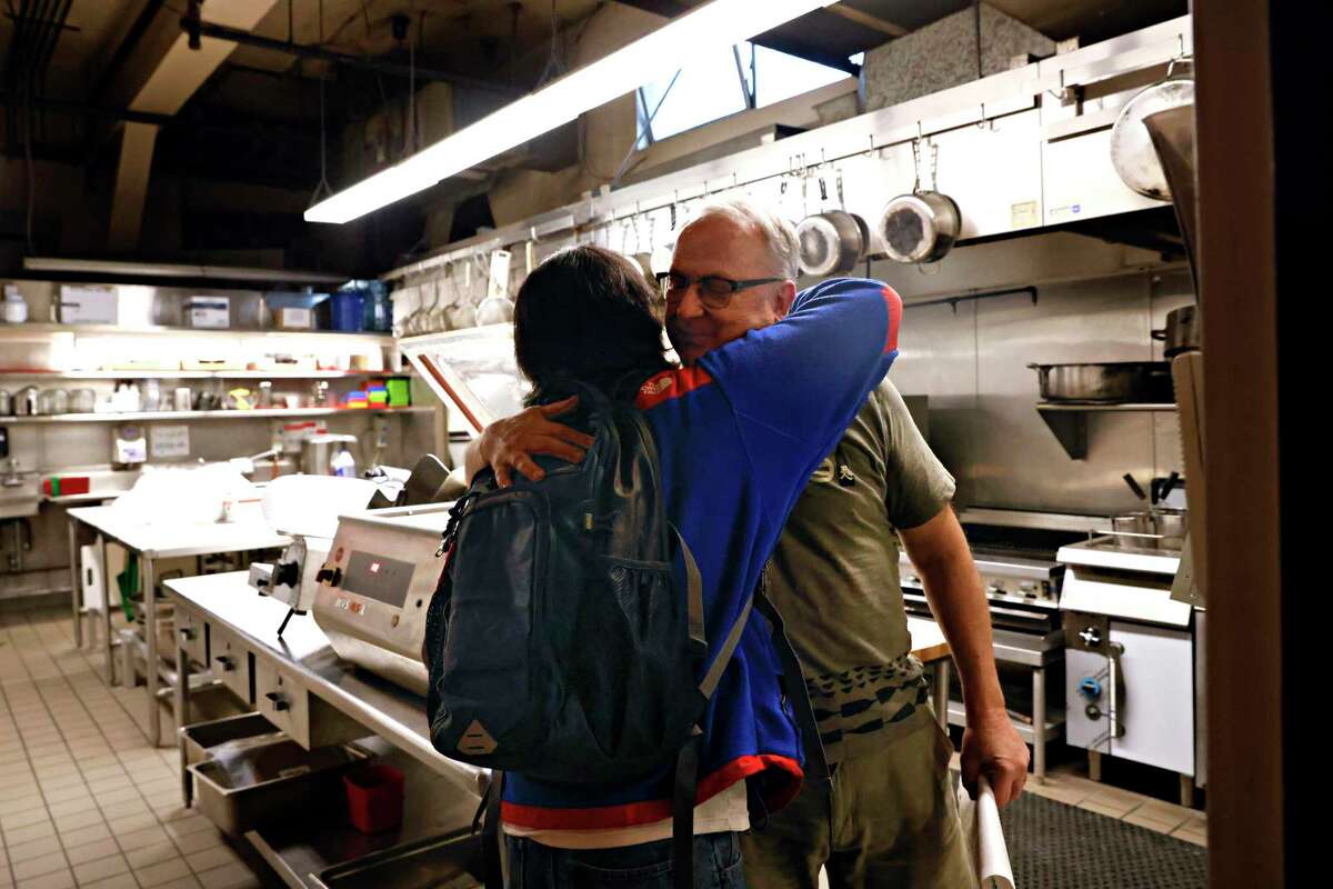 Zero Zero的老板Bruce Hill(右)给酒保Tim Abellera一个拥抱再见。在疫情期间坚持下来后，这家旧金山披萨餐厅于本月关门。