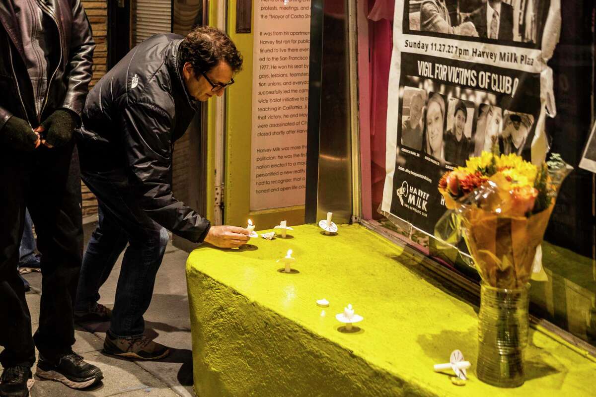 Supervisor Dean Preston places a candle by posters outside 575 Castro Street, formerly Castro Camera and Harvey Milk Residence, during a Sunday night vigil for the 44th anniversary of the assassinations of Harvey Milk and Mayor George Moscone and last week’s mass shooting at Club Q, a LGBTQ club in Colorado Springs, Colo.