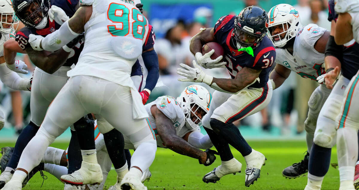 Houston Texans running back Dameon Pierce (31) is tripped up at the line of scrimmage boy Miami Dolphins linebacker Elandon Roberts (52) during the second half of an NFL football game Sunday, Nov. 27, 2022, in Miami Gardens, Fla.