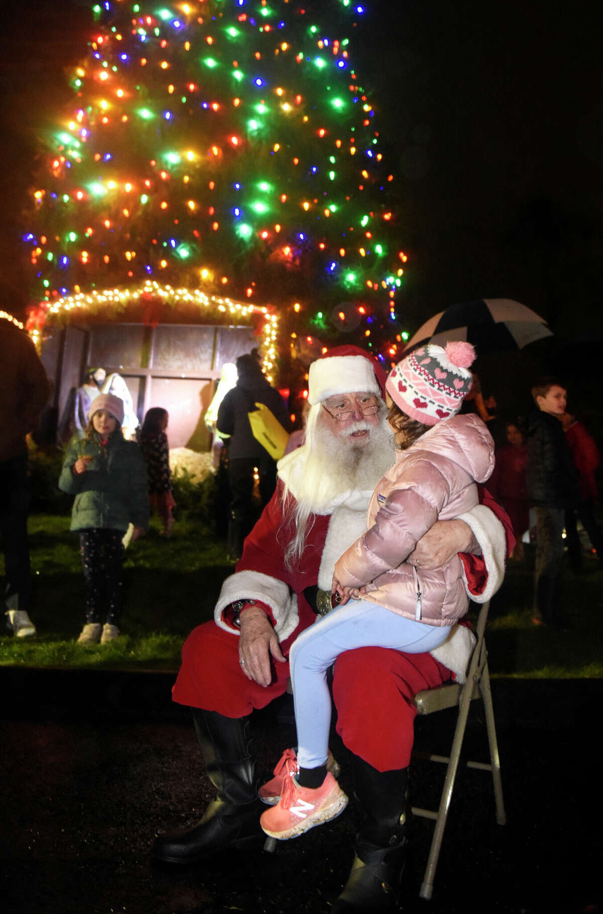 Darien's Camila Visi, 5, sits on Santa's lap at the annual Christmas tree lighting ceremony outside Darien Sport Shop in Darien, Conn. Sunday, Nov. 27, 2022. Santa arrived in the rain Sunday to help light the Christmas tree and pose for photos with children afterwards.