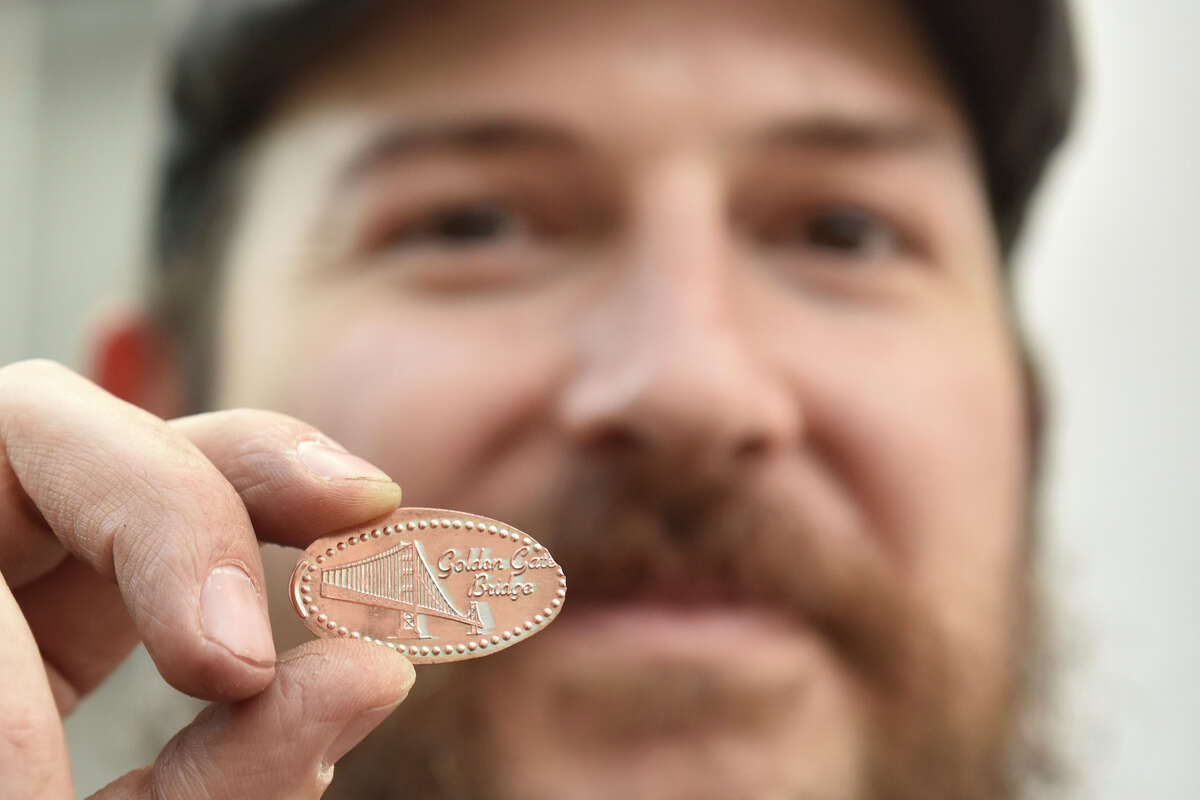 Matthew Sengbusch shows off a souvenir penny during his monthly maintenance sessions of numerous pressed penny machines around Fisherman's Wharf, on Tuesday, Nov. 22, 2022.