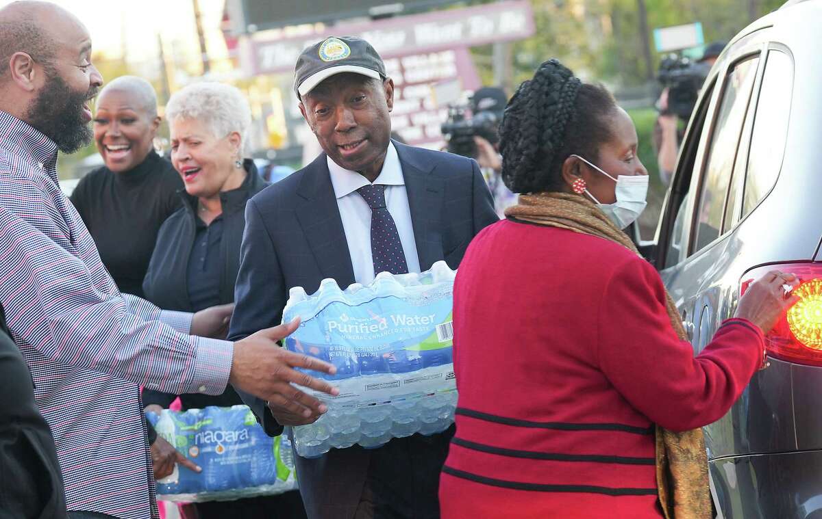 Houston Mayor Sylvester Turner distributes cases of water during a flu-shot drive sponsored by U.S. Rep. Sheila Jackson Lee at Holman Street Baptist Church on Monday, Nov. 28, 2022 in Houston.