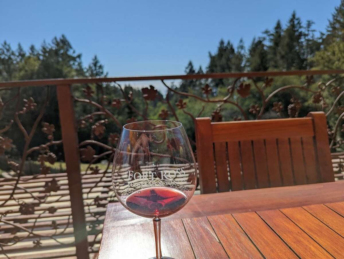 A glass with a small amount of red wine in it sits on an outdoor table at Fort Ross Vineyard & Winery in Jenner, CA. 