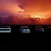 Car are parked near an ancient lava field as a lava flow colors the sky above Mauna Loa, Monday, Nov. 28, 2022, near Hilo, Hawaii. Mauna Loa, the world's largest active volcano erupted Monday for the first time in 38 years.