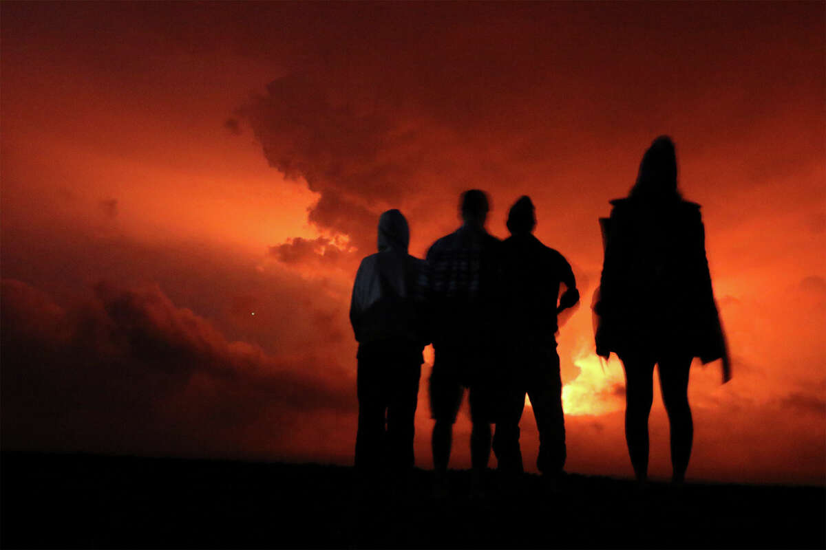 People watch the glow from lava erupting from Hawaii's Mauna Loa volcano, Monday, Nov. 28, 2022, in Hilo, Hawaii.