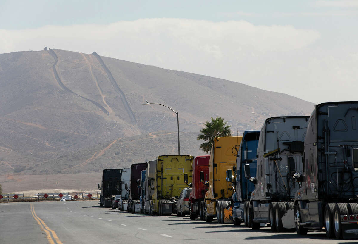A line of semi-trailer trucks line Enrico Fermi Place, a street minutes away from the Otay Mesa Port of Entry, on Thursday, Sept. 23, 2021, in Otay Mesa, California. 