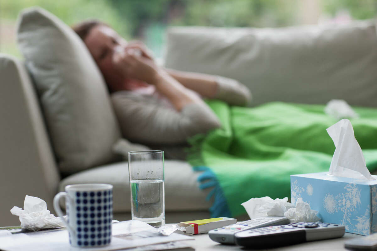 A pistillate   laying connected  a sofa and blowing her nose.