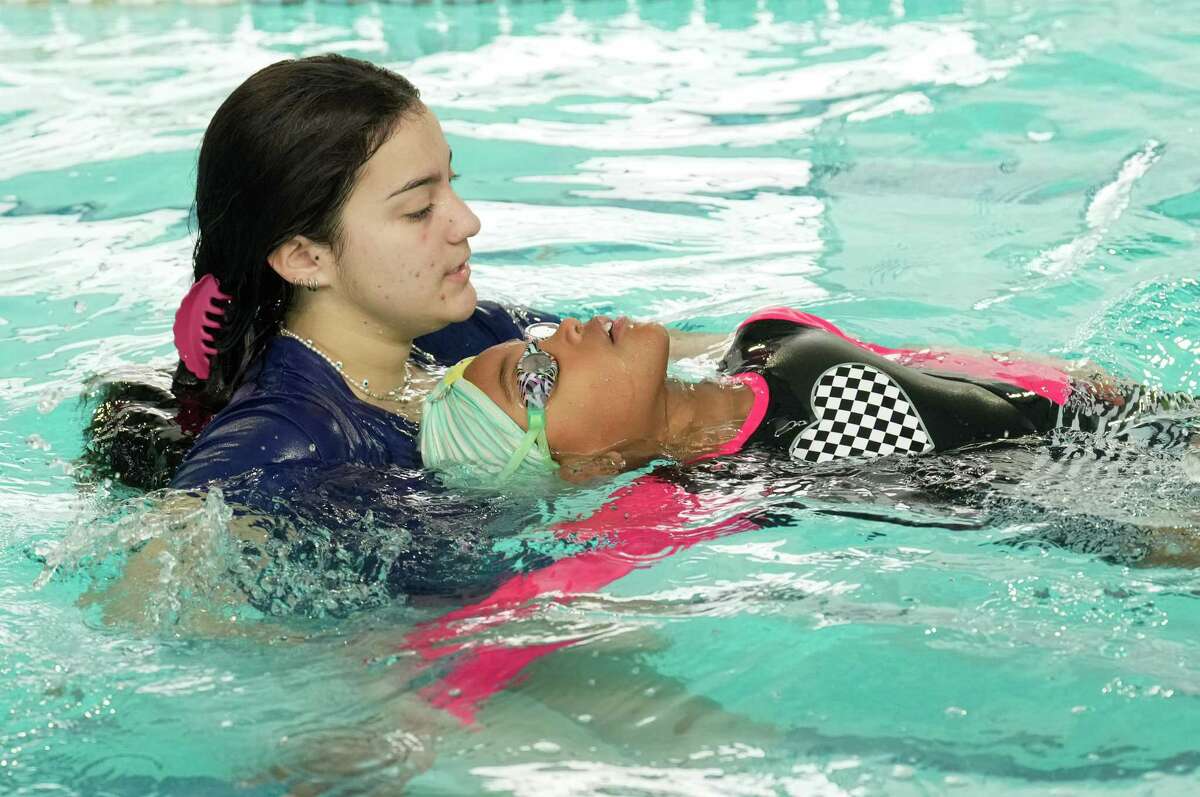 Swimming instructor Paula Garzon teaches Emilie Ellis how to backstroke at a swim camp Tuesday, Nov. 29, 2022, at Wolfies Swim Camp in Houston. Wolfies Swim Camp had a pop-up day camp for children affected by the HISD school closure.