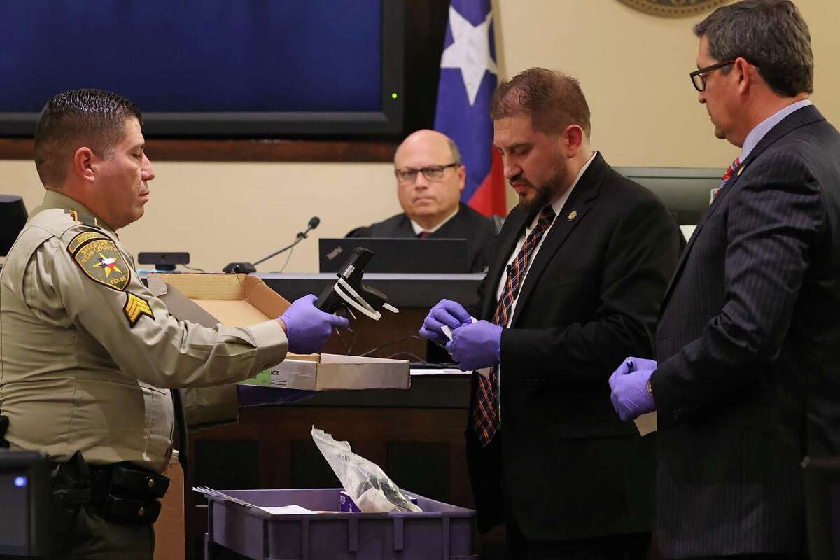 Webb County Sheriff’s Sgt. Roberto M. Castillo, left, presents a gun for labeling as evidence during the capital murder trial of former U.S Border Patrol supervisor Juan David Ortiz on Tuesday. Ortiz is accused of killing four women in Laredo in 2018.