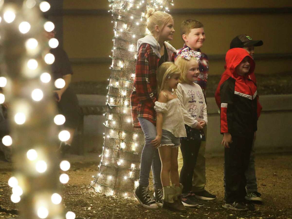Children pose for a photo in downtown Conroe before the city’s Christmas tree lighting celebration at Heritage Place Park, Tuesday, Nov. 29, 2022. Aside from Conroe's official Christmas tree, the park is decorated in white lights for the season. 