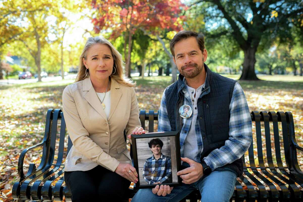 Laura and Chris Didier, the parents of Zach Didier, who died at age 17 after taking a fake prescription pill that contained fentanyl, hold one of his senior photographs at a bench installed in his honor in Sacramento on Nov. 13. "It should never have happened with Zach and it should never happen again. No one should be suffering like this," Chris said.
