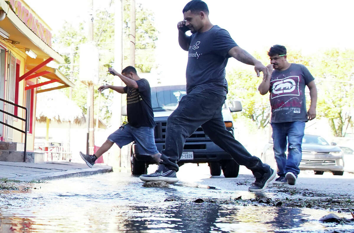 Customers at Laredo Taqueria try to keep dry as they step over an ever-growing puddle from water flowing out of the ground on Wednesday, Nov. 30, 2022 in Houston.