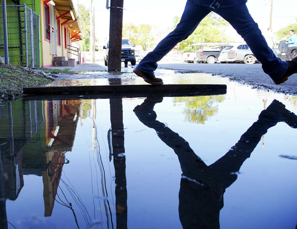 Customers at Laredo Taqueria try to keep dry as they step over an ever-growing puddle from water flowing out of the ground on Wednesday, Nov. 30, 2022 in Houston.
