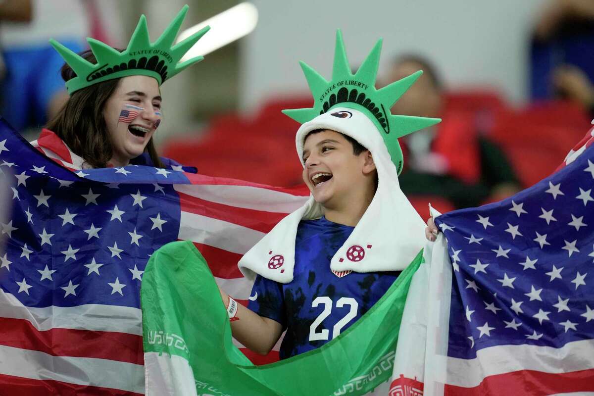 Wrapped up in the World Cup, two young United States soccer fans hold up American and Iranian flags before Tuesday's Group B match, won 1-0 by the U.S., at the Al Thumama Stadium in Doha, Qatar.