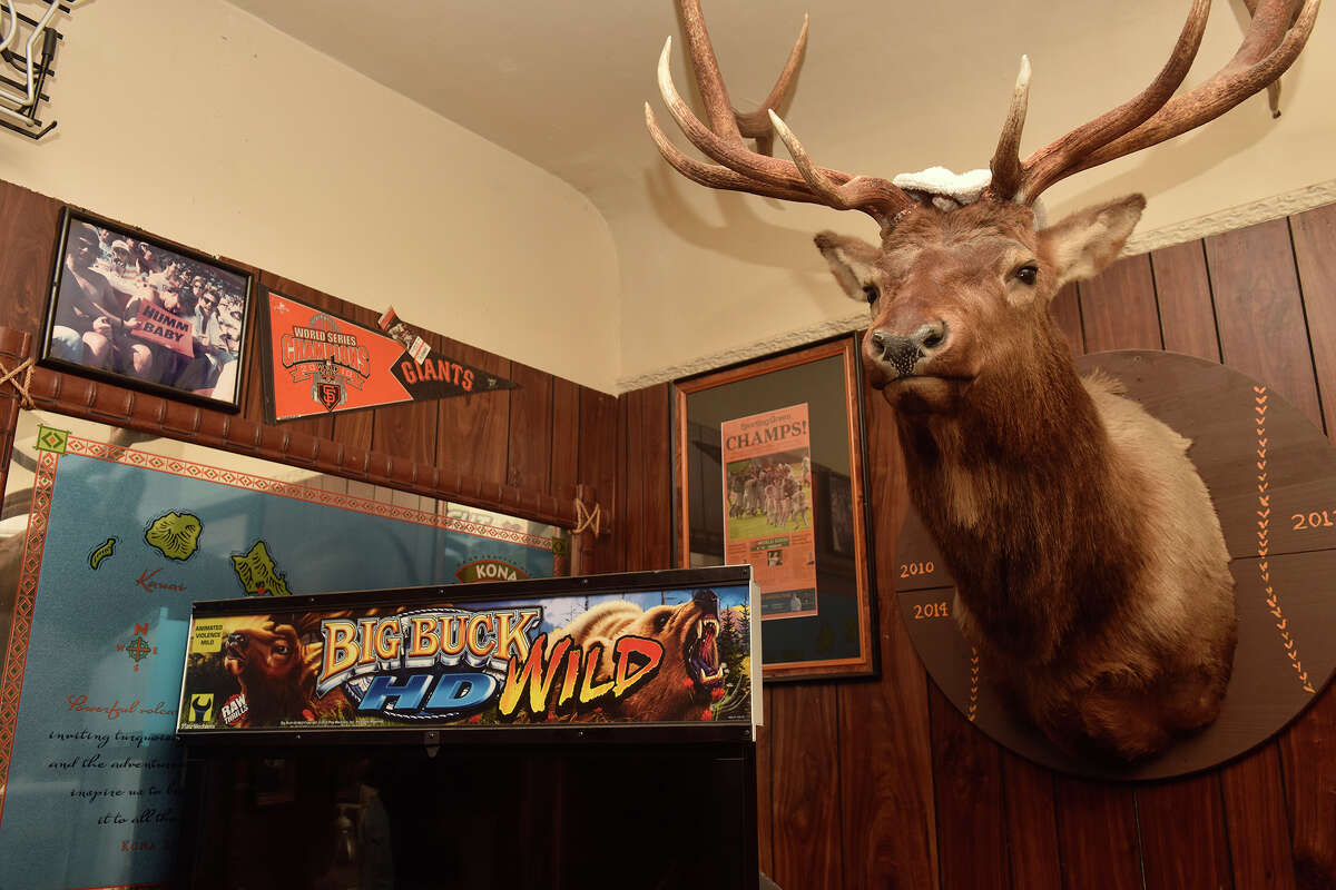 A Big Buck Hunter video game stands beneath a stuffed buck that was given to Mauna Loa owner Curtis Martin from former SF Giants manager Bruce Bochy. 