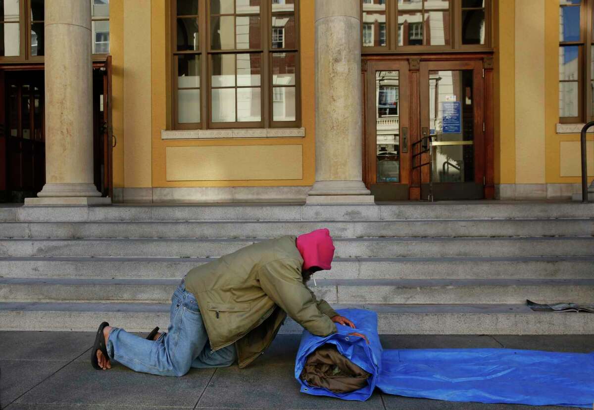 A member of the homeless camp "First they Came for the Homeless" rolls up and blanket and a tarp outside of the US Postal Office on Allston Way in 216 in downtown Berkeley, Calif.