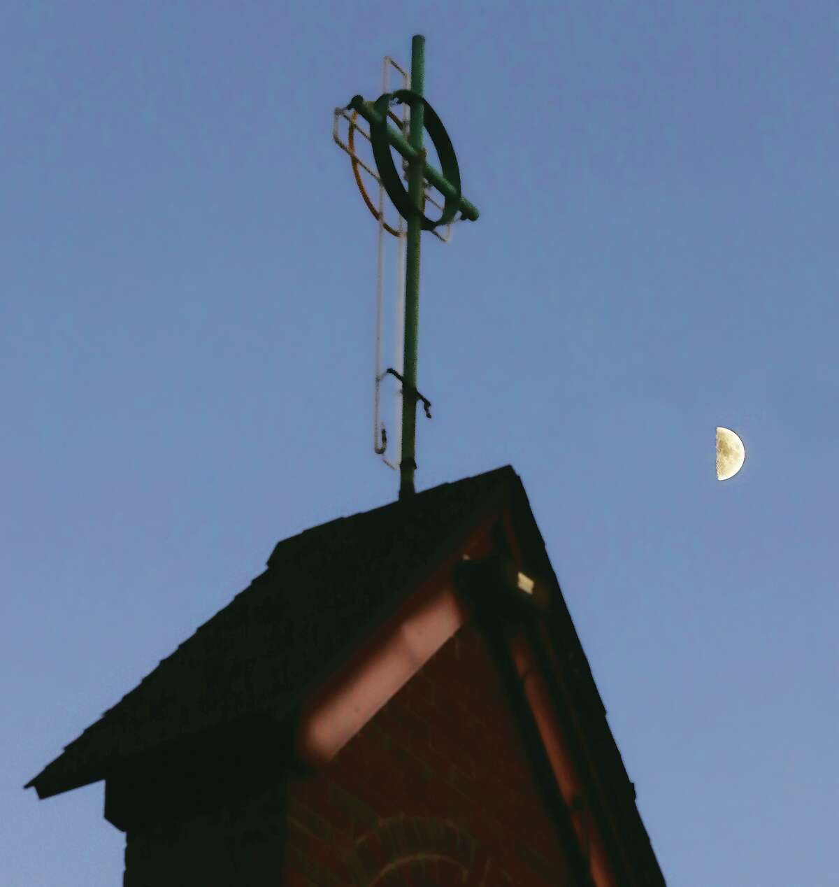 John Badman|The Telegraph A half moon shines in the sky Wednesday evening behind the cross above the Messiah Lutheran Church on Milton Road in Alton.