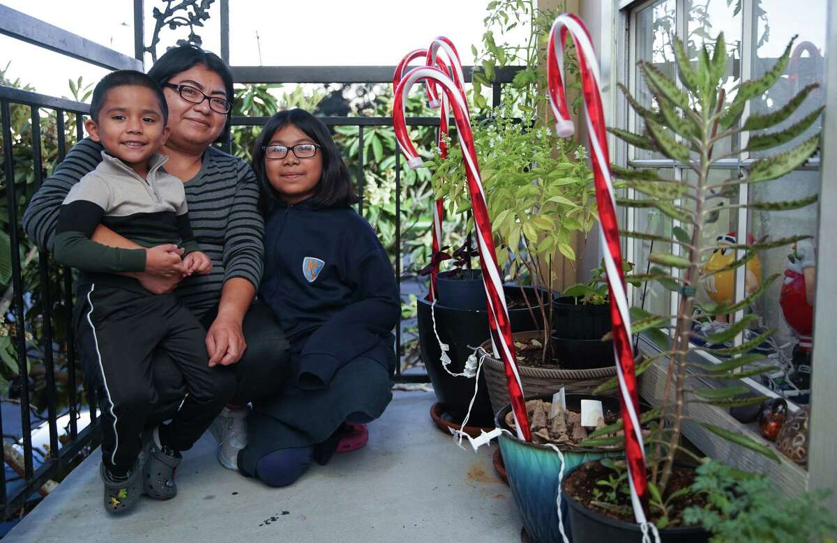 Luz Perez with her nephew and daughter sit next to her porch garden at her Gulfton apartment on Wednesday, Nov. 30, 2022 in Houston.