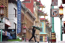 A pedestrian crosses Grant Avenue in Chinatown, during rain showers on Thursday, Dec. 1, 2022.