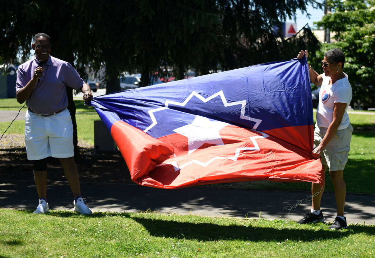 Dave Fields and Jere Eaton present the Juneteenth flag during a Juneteenth celebration at Jackie Robinson Park in Stamford, Conn. Sunday, June 19, 2022. 