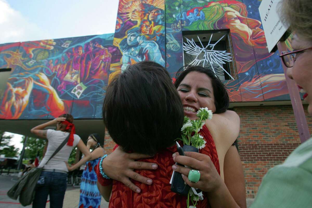 Adriana Garcia receives a hug from a friend at the Aug. 25, 2007, dedication of her mural “Brighter Days.” The work adorns the brick facade of what was then a mental health clinic on San Antonio’s West Side. The building is now owned by a law firm, which wants to remove the mural.