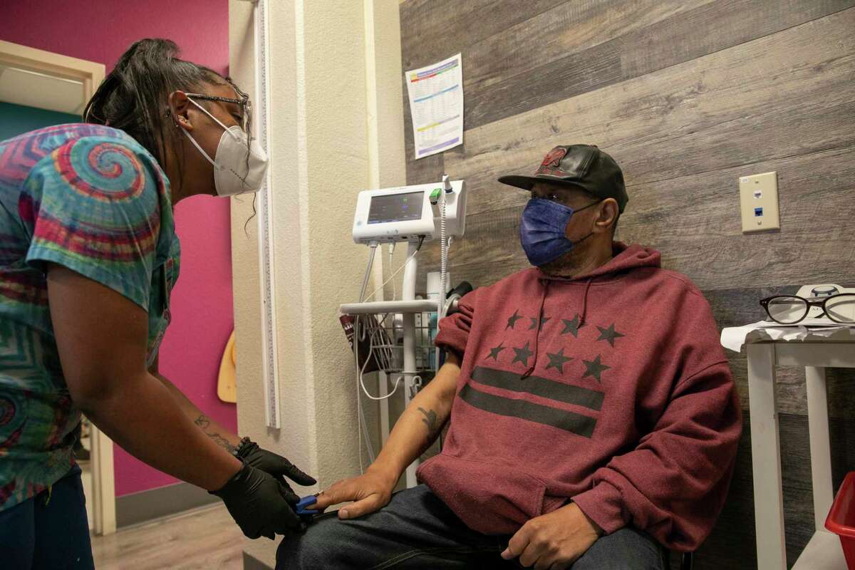 2022年11月30日，在加利福尼亚州奥克兰市的根社区卫生中心，医疗助理拉特里什·皮茨从罗纳德·杨的手指上测量脉搏血氧计。研究表明，常见的医疗设备通常会高估深皮肤患者的氧含量，这可能会导致COVID-19死亡人数的差异。罗茨要求11家制造商改进脉搏血氧仪，否则将面临潜在的法律诉讼。