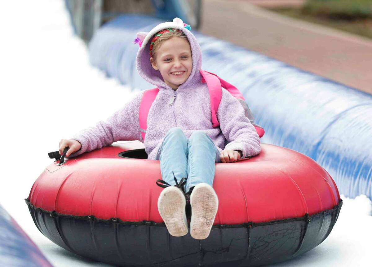 Mikaylyn Parker slides down an ice slide during the annual Conroe Christmas parade, Saturday, Dec. 11, 2021, in Conroe. This year’s Christmas celebratio is set for Saturday in downtown Conroe.