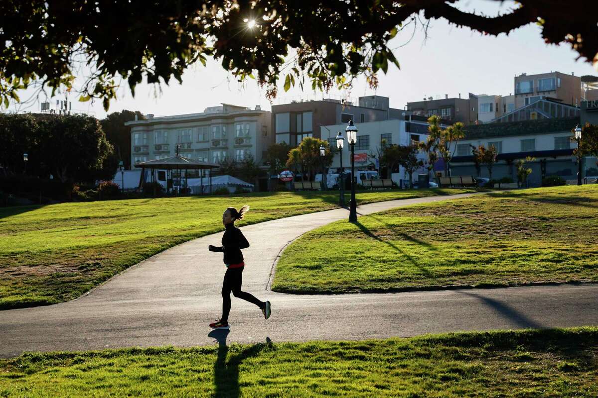 A runner makes their way down the grassy hill near Hyde Street at Aquatic Park in San Francisco.