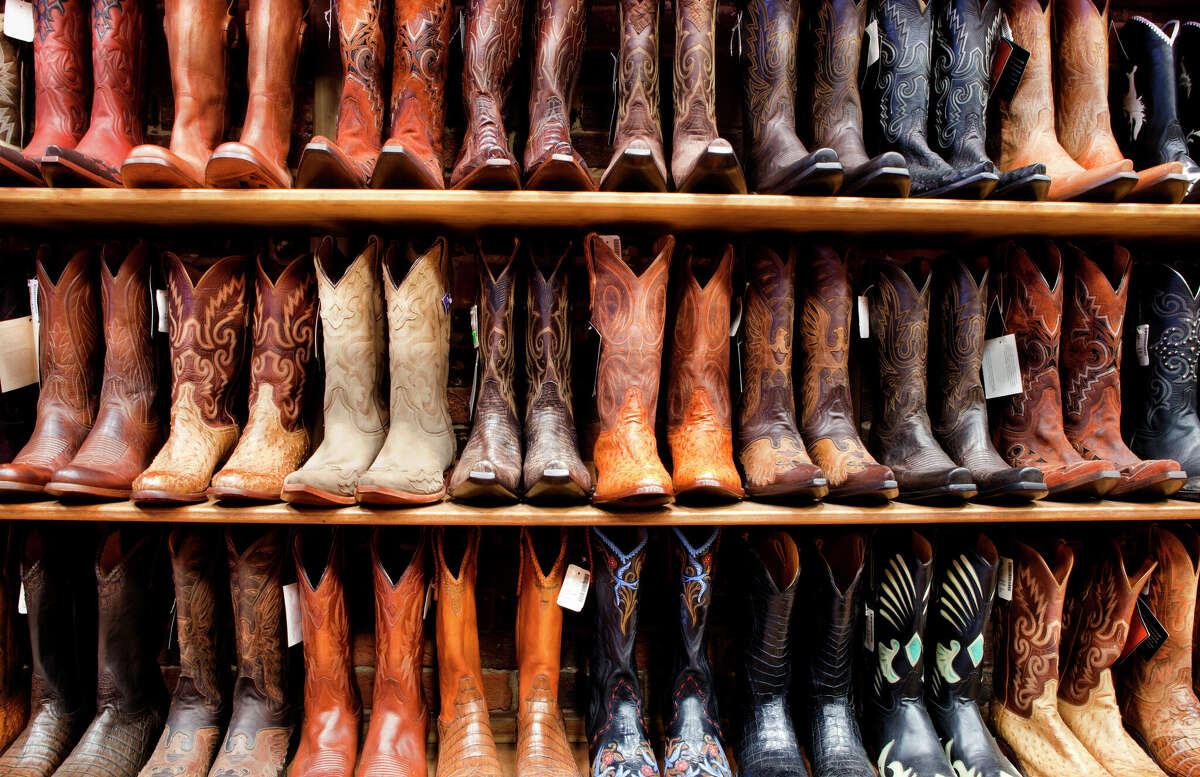 A shelf is filled with a wall of cowboy boots.