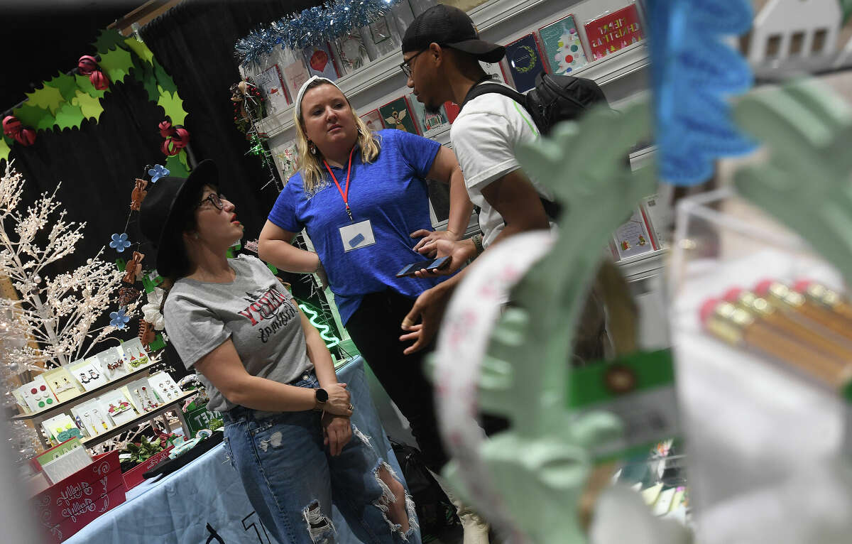 From left, Sophia Bouey and Print Doodle Press owner Megan Buchta talk with Kenyan Guidry at Buchta's booth in the annual Junior League of Beaumont's Main Street Market. Photo made Friday, December 2, 2022 Kim Brent/Beaumont Enterprise