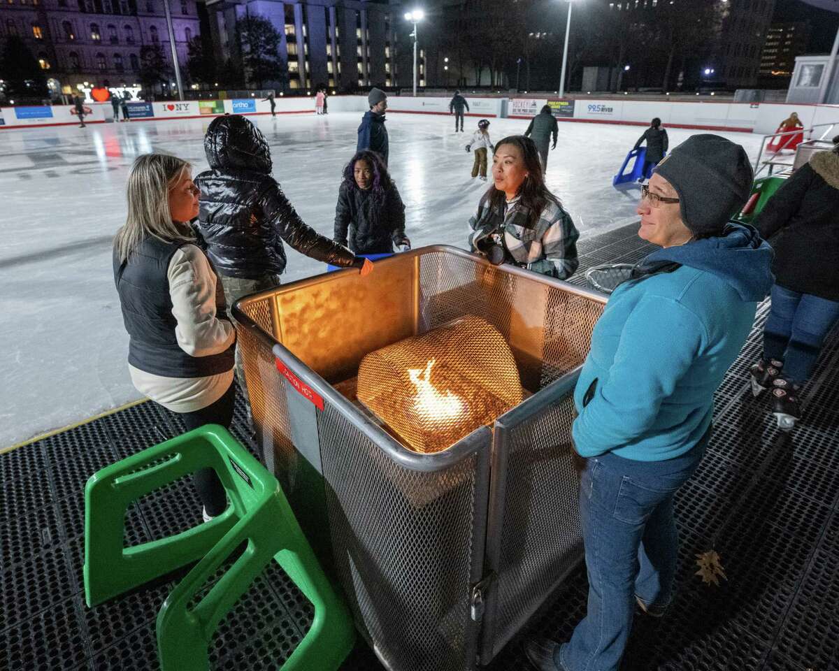 Skaters keep warm around a fire pit at the Empire State Plaza skating rink. The rink opened for the season on Friday, Dec. 2, 2022, in Albany, NY. Hours of operation are Tuesday through Friday noon to 3:30 p.m. and 4:30 to 8:30 p.m. and Saturday and Sunday from noon to 2 p.m., 3 to 5 p.m. and 6 to 8 p.m. Rink hours are weather dependent. (Jim Franco/Times Union)