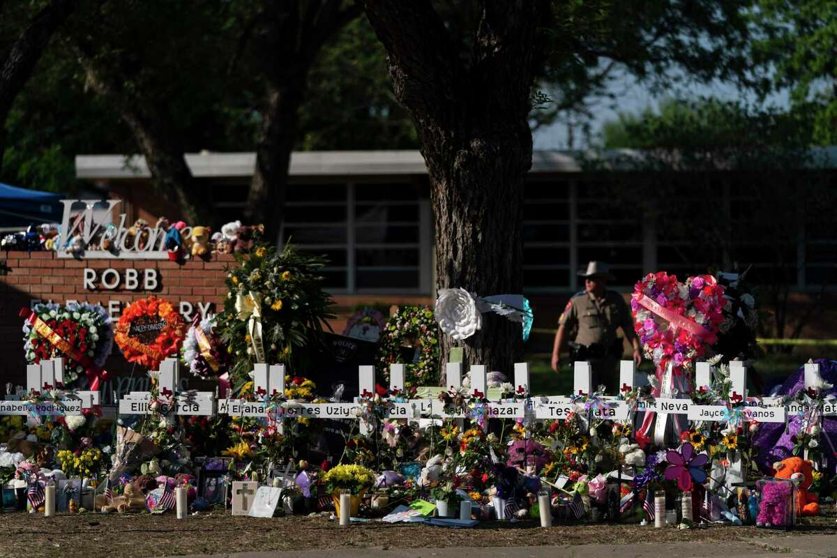 FILE - Flowers and candles are placed around crosses on May 28, 2022, at a memorial outside Robb Elementary School in Uvalde, Texas, to honor the victims killed in the school shooting a few days prior. Victims of the Uvalde school shooting that left 21 people dead have filed a lawsuit seeking $27 billion against local and state police, the city and other school and law enforcement officials for failing to follow active shooter protocol because authorities waited more than an hour to confront the attacker inside a fourth-grade classroom, according to court documents.