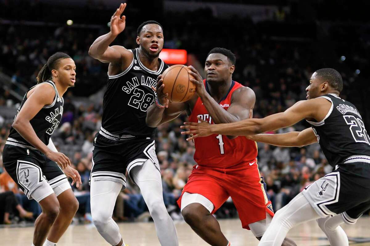 New Orleans Pelicans' Zion Williamson (1) drives between San Antonio Spurs' Malaki Branham, right, and Charles Bassey (28) as Spurs guard Romeo Langford, left, watches during the second half of an NBA basketball game, Friday, Dec. 2, 2022, in San Antonio. (AP Photo/Darren Abate)