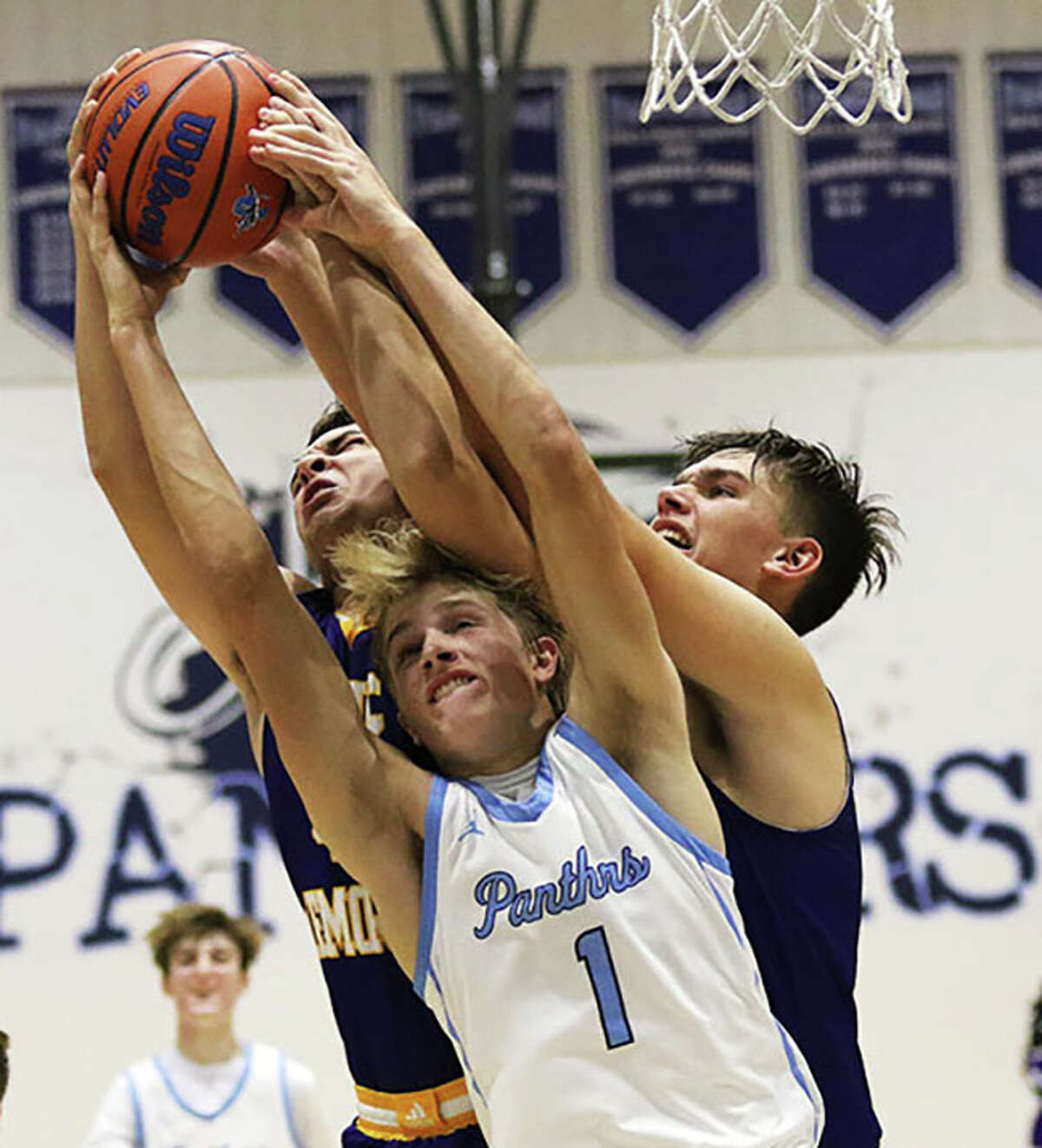 Jersey's Francis Vogel (1) battles CM's Sam Buckley (right) and Dalton Buhs for a rebound in a MVC boys basketball game Friday night at Havens Gym in Jerseyville. 