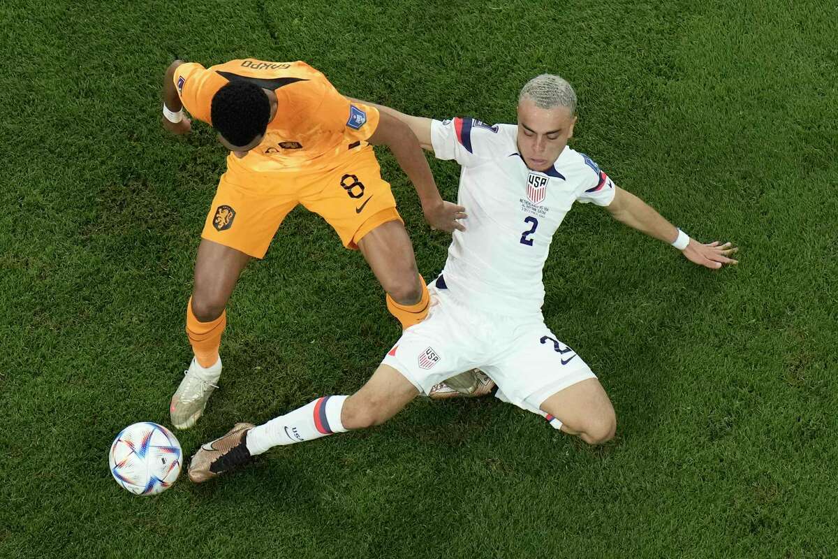 Cody Gakpo of the Netherlands, left, challenges for the ball with Sergino Dest of the United States during the World Cup round of 16 soccer match between the Netherlands and the United States, at the Khalifa International Stadium in Doha, Qatar, Saturday, Dec. 3, 2022. (AP Photo/Hassan Ammar)
