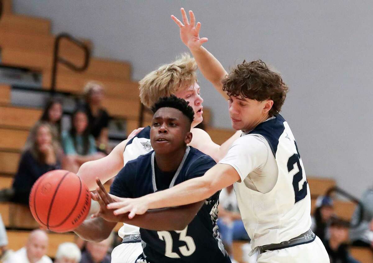 College Park guard Justus Turner (23) makes a pass between Tomball Memorial small forward Luke Reder (2) and guard Emilio Varela (22) in the first quarter of a non-district high school basketball game at Grand Oaks High School, Saturday, Dec. 3, 2022, in Spring.