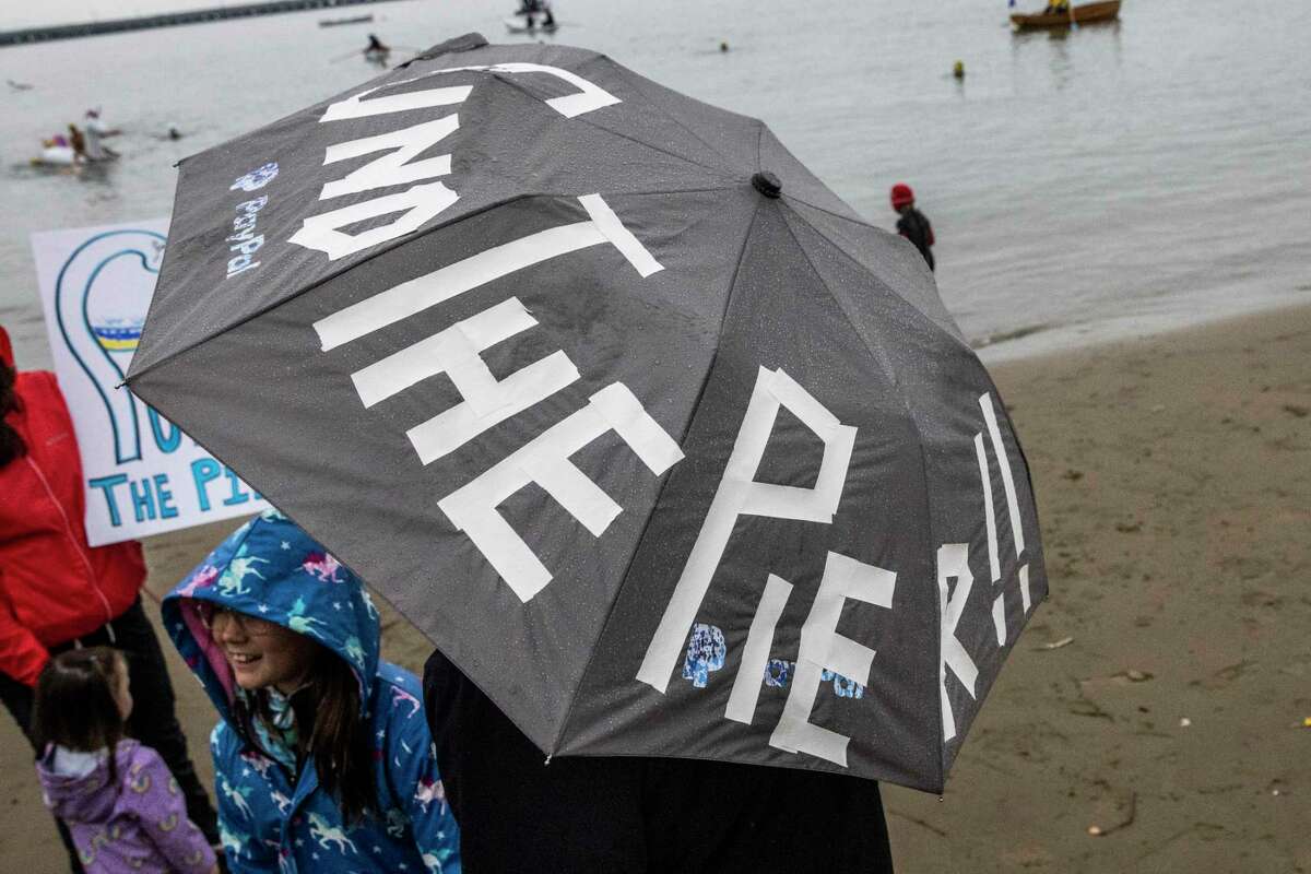 Victor Corral holds an umbrella saying “Fund The Pier” during a rally to save the Municipal Pier in San Francisco on Dec. 3, 2022. Sen. Alex Padilla is seeking $15 million in next year’s federal budget to get work started.