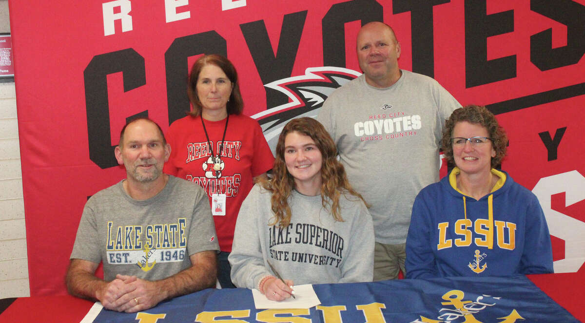 Nora Smoes, with her parents Dan and Sarah Smoes sitting with her, and her Reed City cross country co-coaches Susan and Rich Saladin standing behind her, signed a national letter of intent on Friday to run at Lake Superior State.
