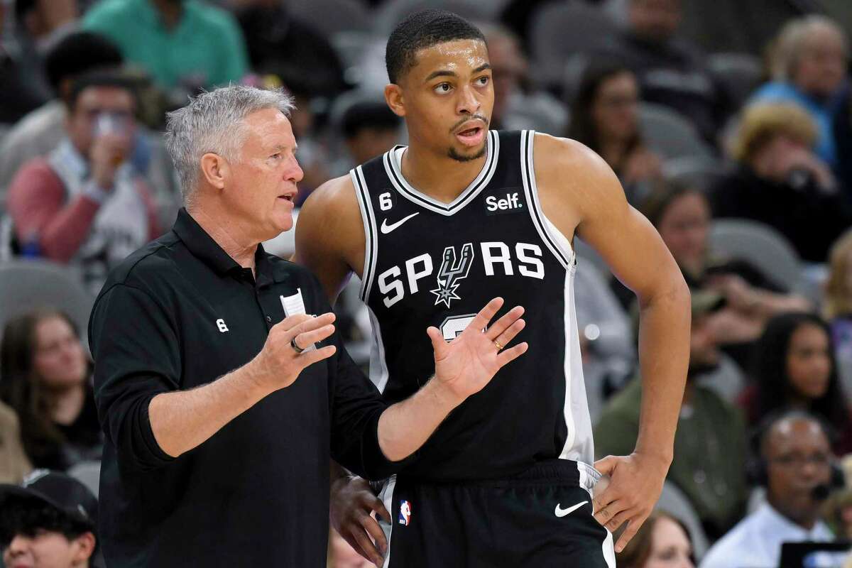 Spurs assistant coach Brett Brown, left, talks with forward Keldon Johnson during an NBA game. 