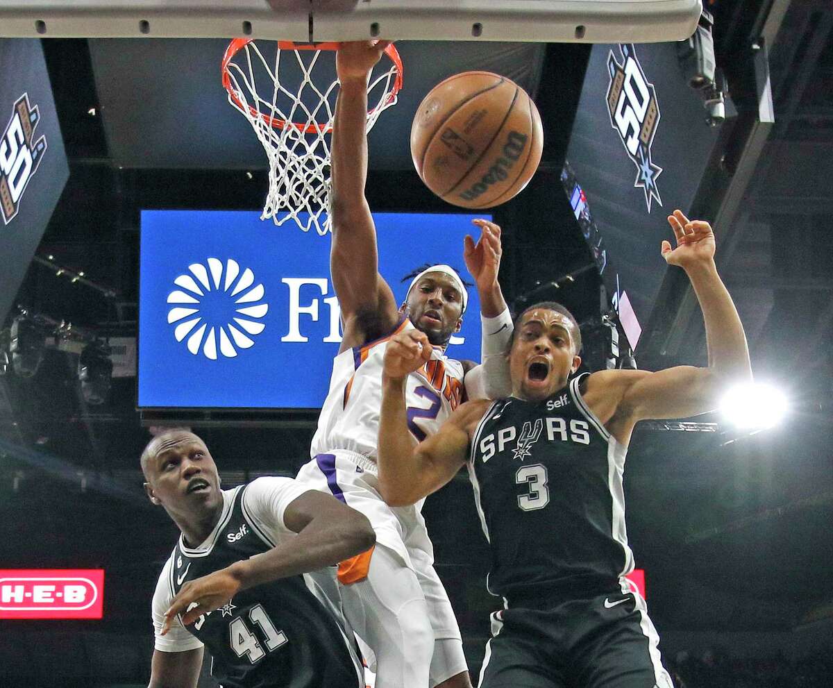 The Spurs’ Keldon Johnson and Gorge Dieng battle the Phoenix Suns’ Josh Okogie (2) for a rebound in the second half Sunday.
