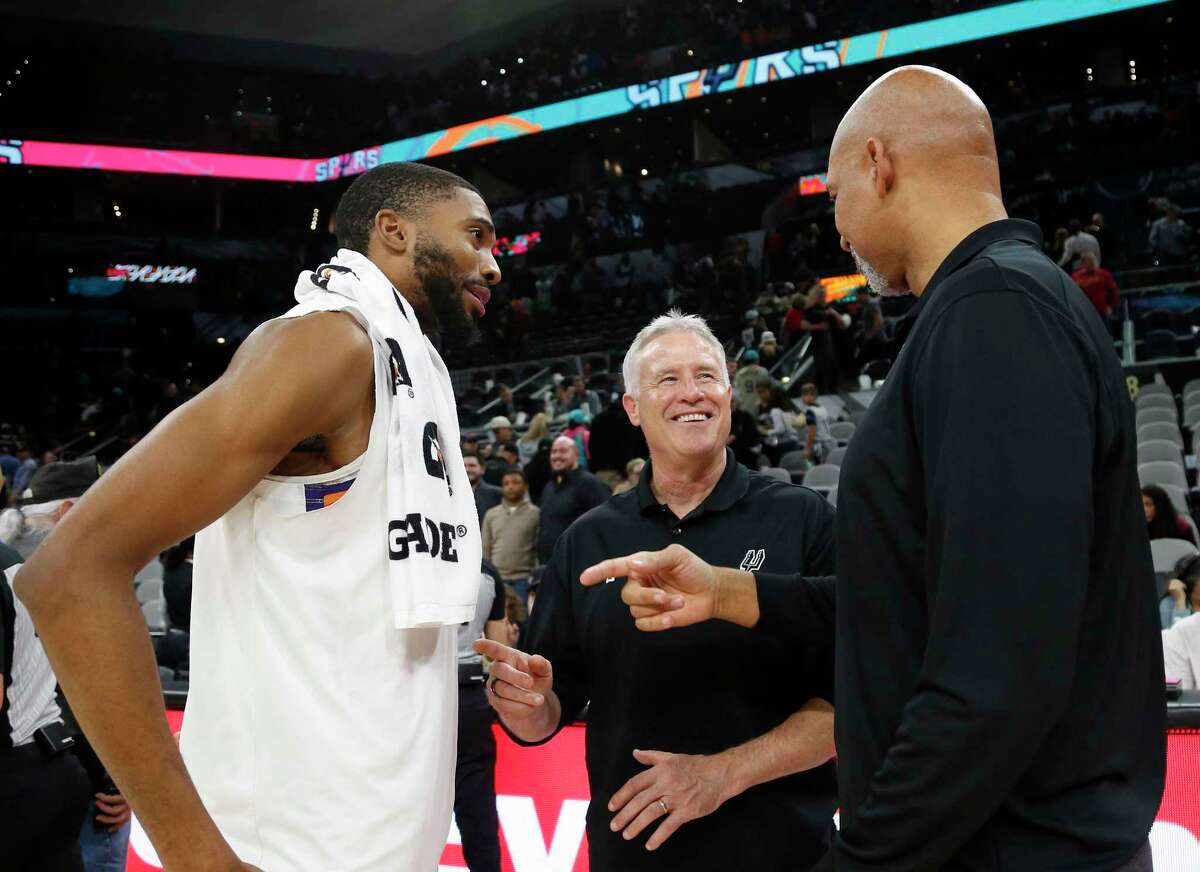 Suns head coach Monty Williams and Mikal Bridges talk with Spurs assistant coach Brett Brown during Sunday’s game at AT&T Center.